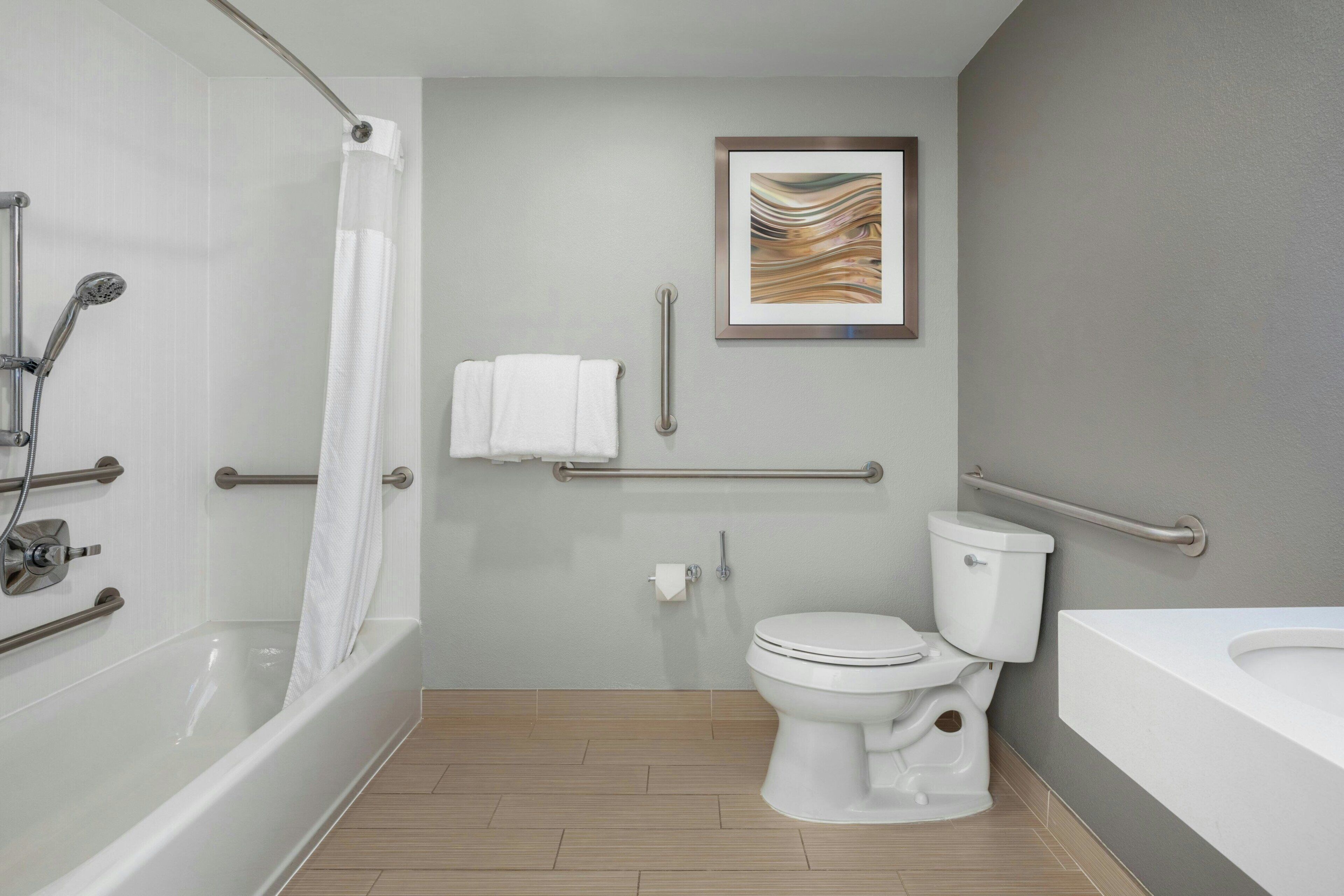 Een moderne badkamer met een bad, toilet en douche.
