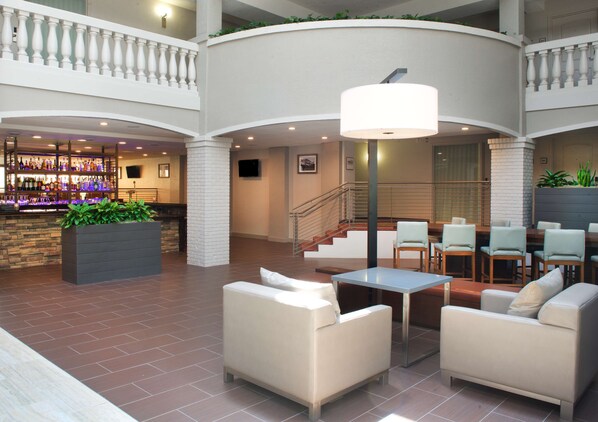 A spacious lobby with a bar area, seating arrangements, and a staircase.