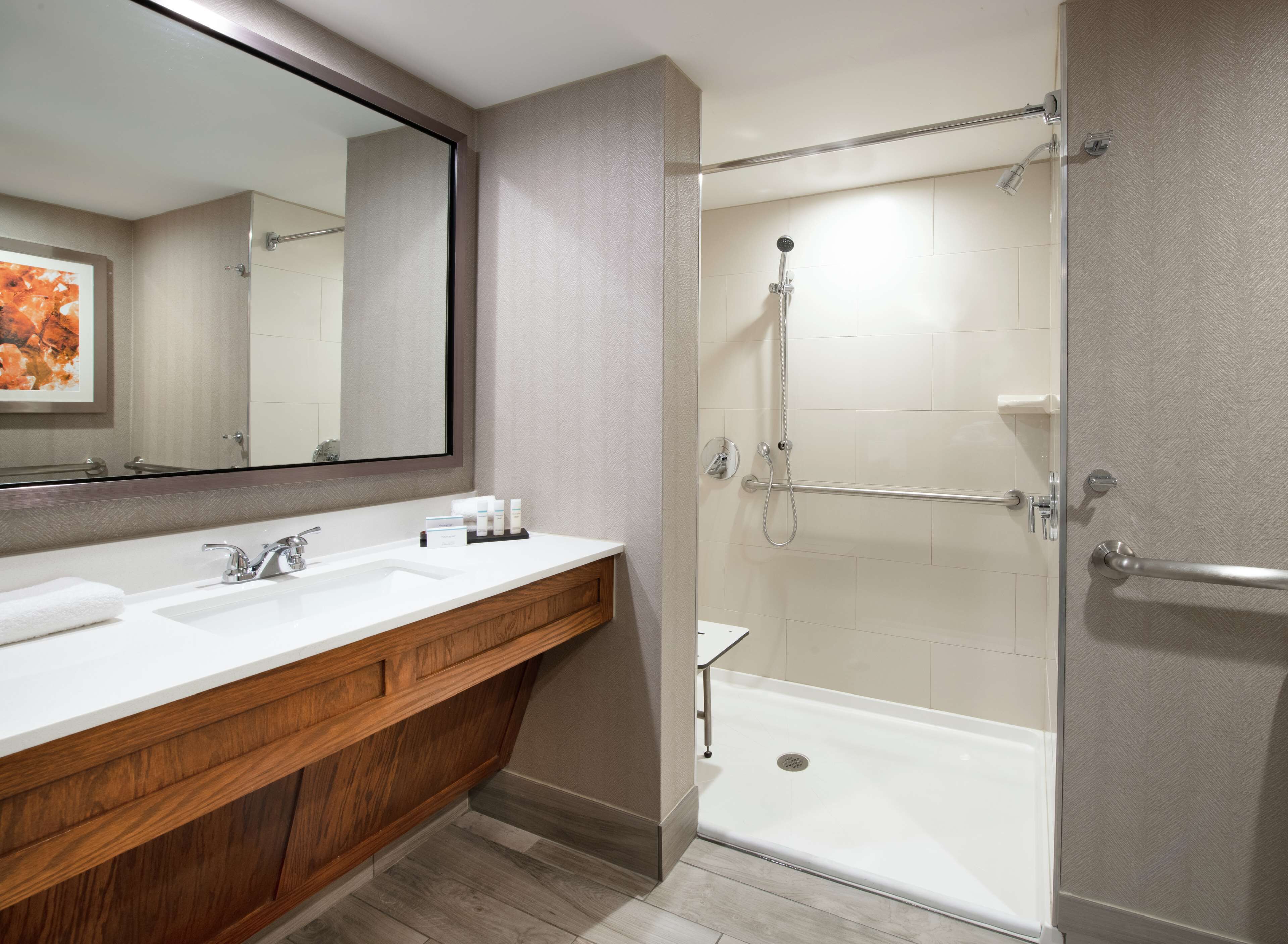 A bathroom with a wooden vanity, a large mirror, a shower with a glass door, and a bathtub.