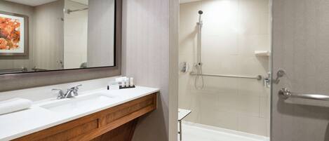 A bathroom with a wooden vanity, a large mirror, a shower with a glass door, and a bathtub.