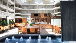 A multi-level atrium with a central bar area, dining tables, and a water feature. - Embassy Suites by Hilton Colorado Springs (Colorado Springs)