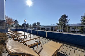A rooftop deck with lounge chairs, a lamp, and a view of mountains and parked cars. - Embassy Suites by Hilton Colorado Springs (Colorado Springs)