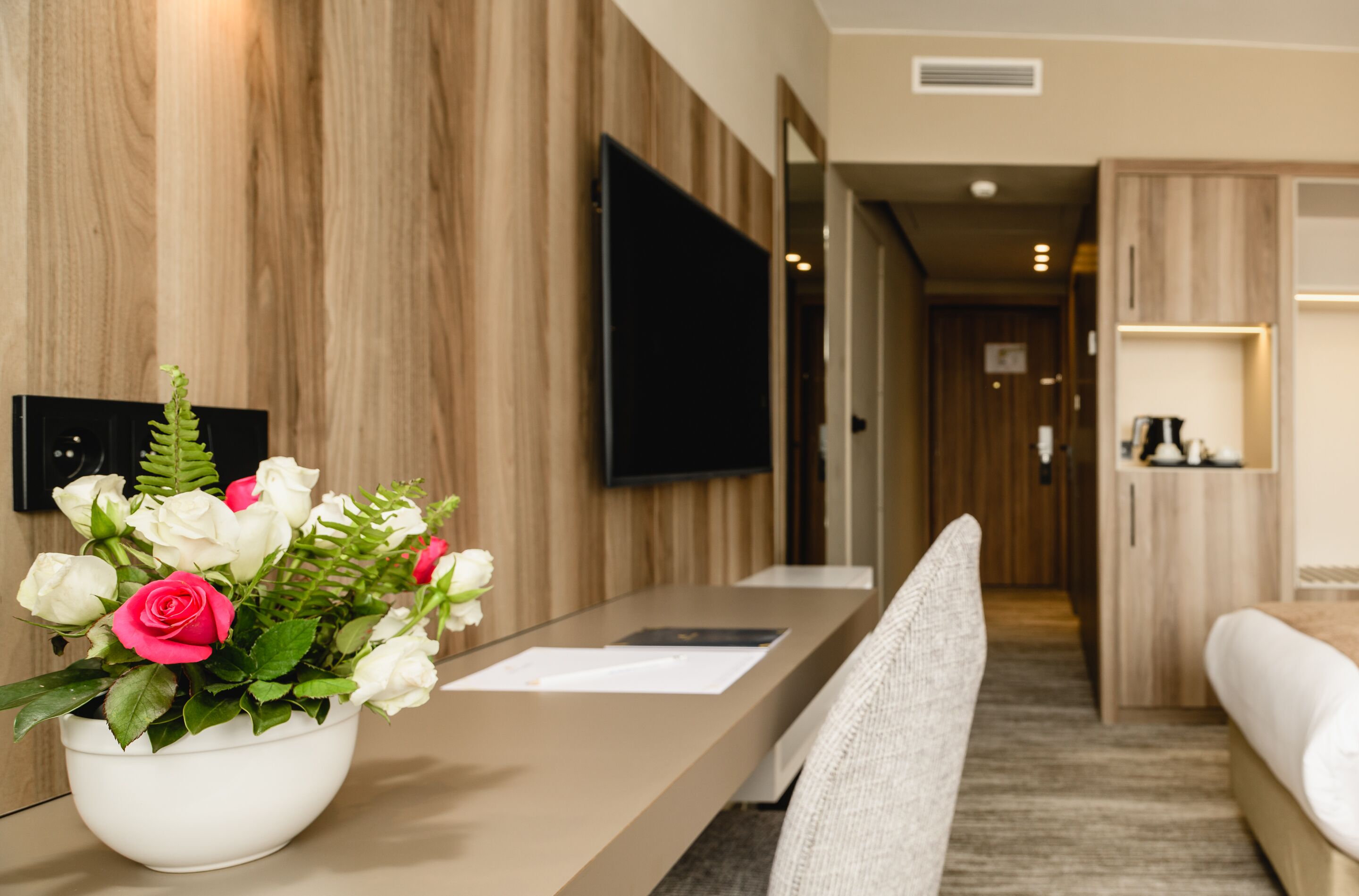 Un espace d’accueil d’hôtel avec un mur en bois, un téléviseur à écran plat, un comptoir de réception et un canapé.