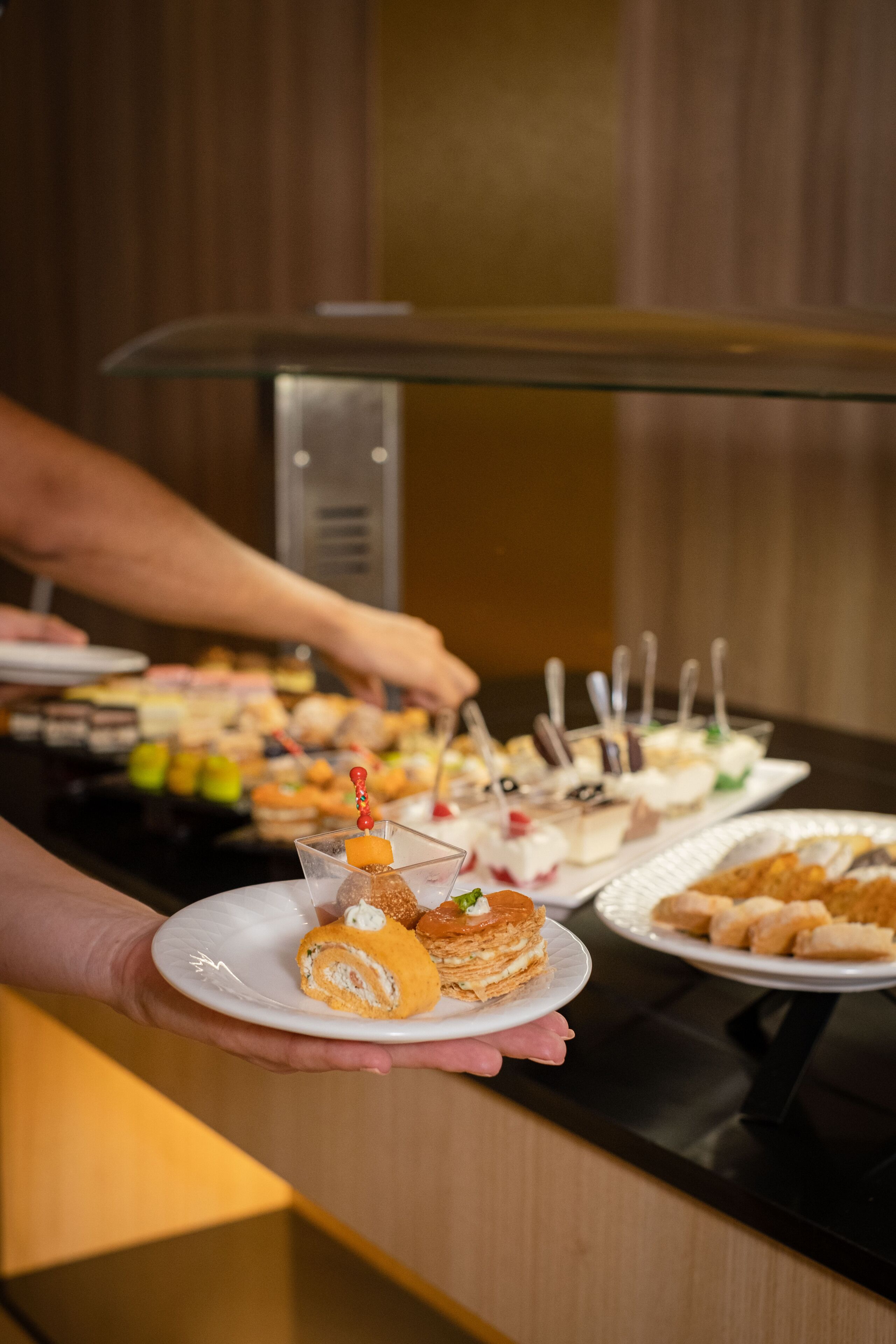 Ein Buffet mit verschiedenen Desserts und einer Person, die Speisen serviert.