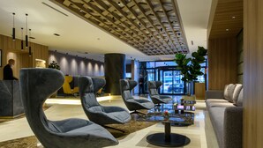 Un lobby moderno con sillones tapizados en gris, una mesa de centro y un sofá.