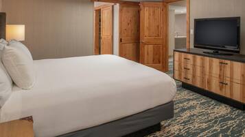 A hotel room with a bed, a television, a wooden wardrobe, and a bathroom visible through an open door.