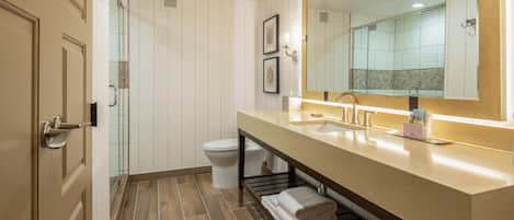 A modern bathroom with a long vanity, a large mirror, and a shower area.