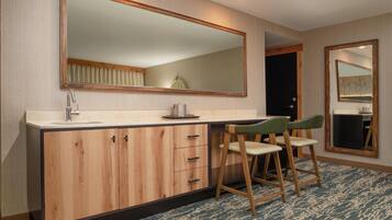 A modern bathroom with a wooden vanity, a large mirror, and two bar stools.