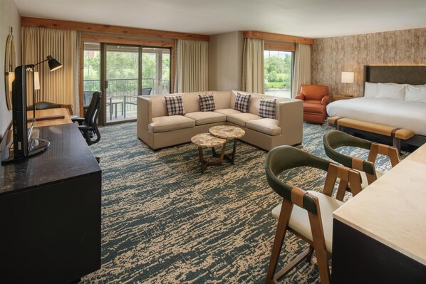 A hotel room with a sofa, a bed, a desk, a chair, and a small table. - Edgewater Missoula, Tapestry Collection by Hilton (Missoula)