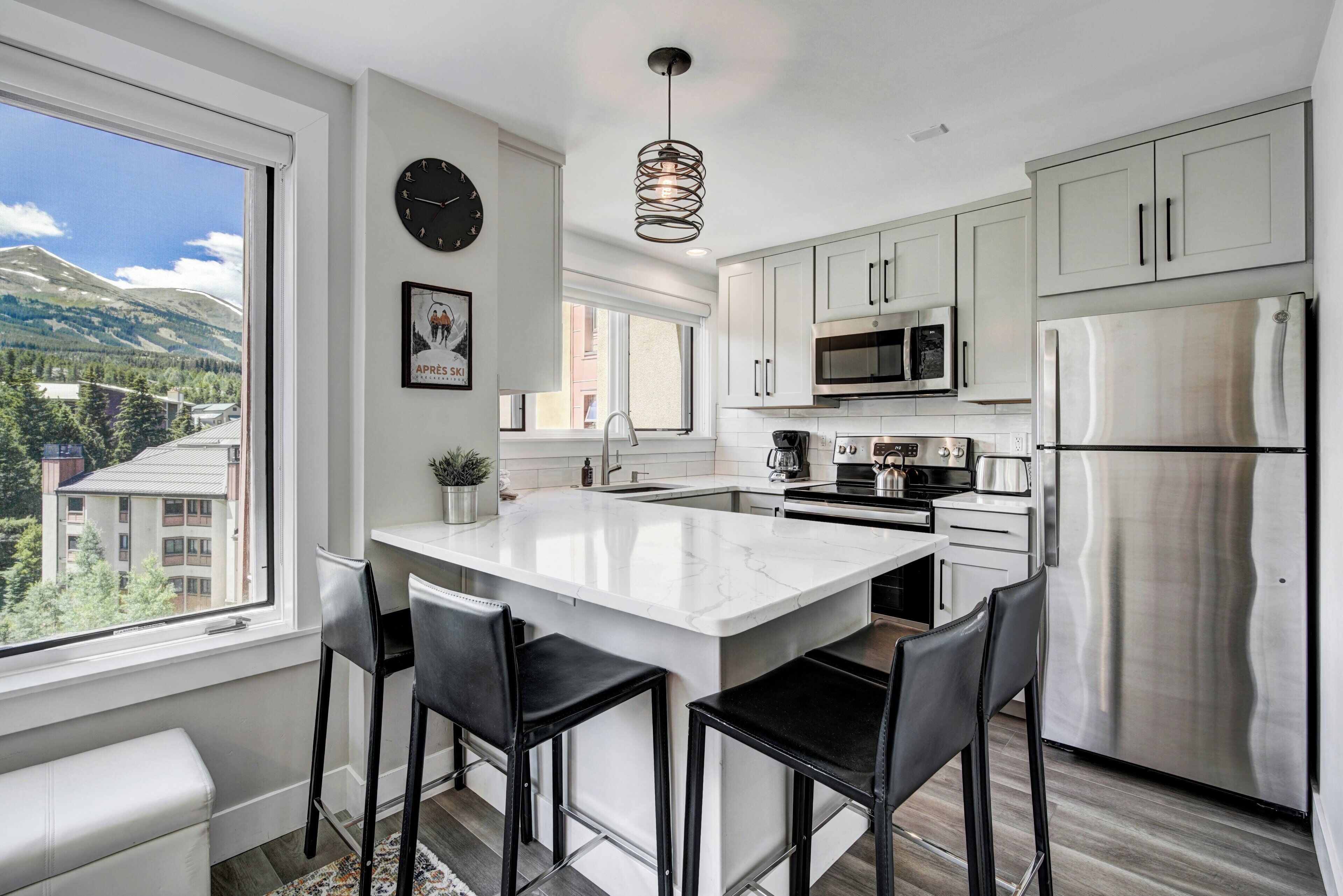 A modern kitchen with a central island, stainless steel appliances, and a view of the mountains.