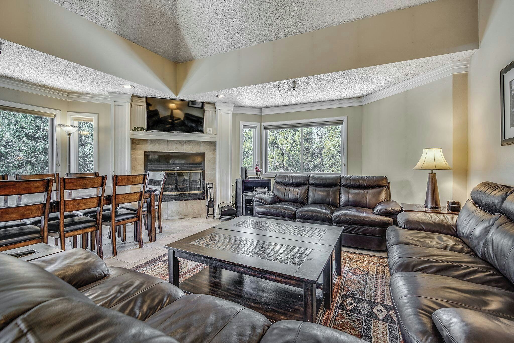 Un salón amplio con sofás de cuero, una chimenea y ventanas grandes.