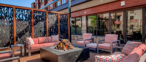 An outdoor seating area with sofas and chairs, a fire pit, and a view of a building with a 'NO Access' sign.