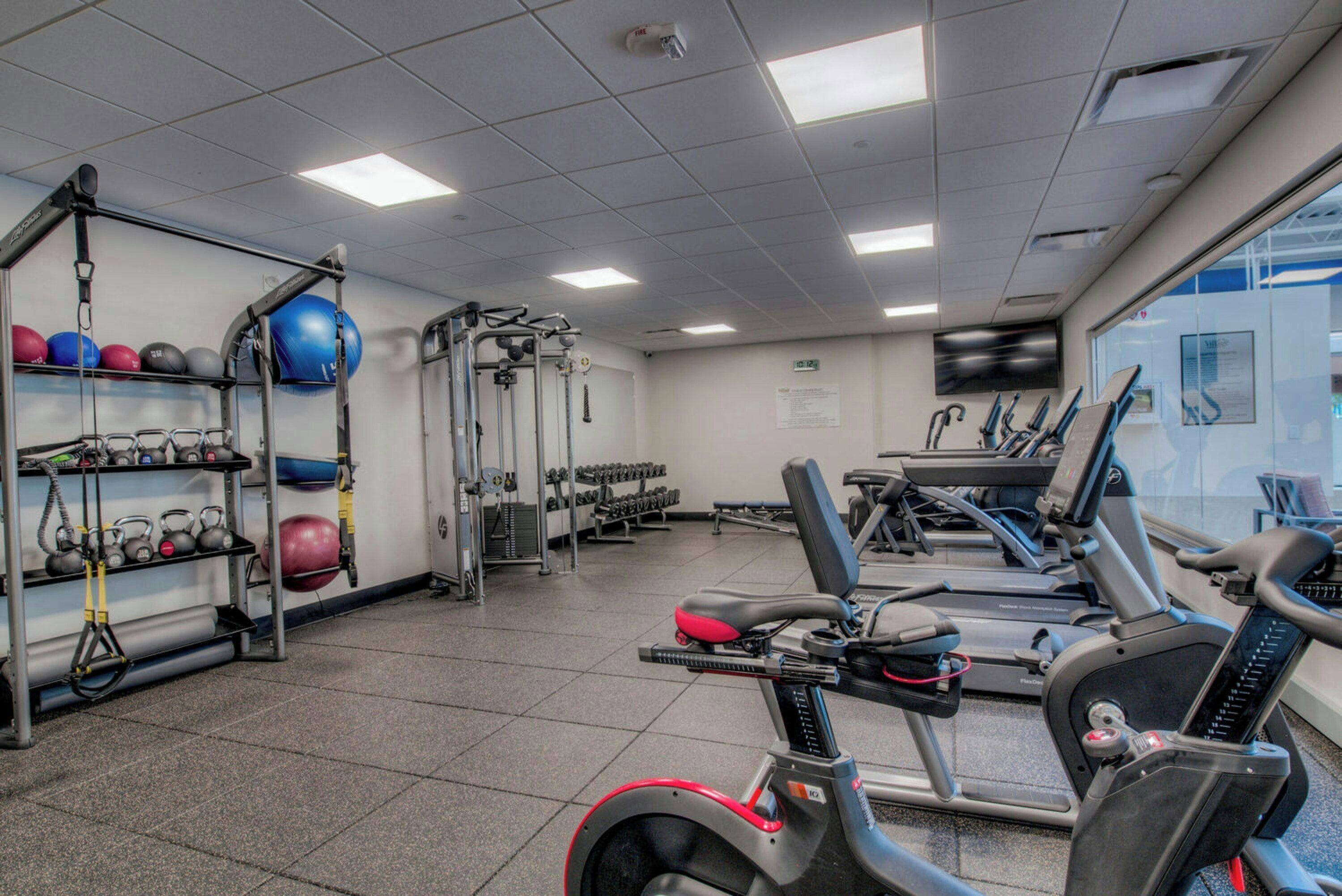 Una palestra con tapis roulant, macchinari per pesi e diverse attrezzature per l'allenamento.