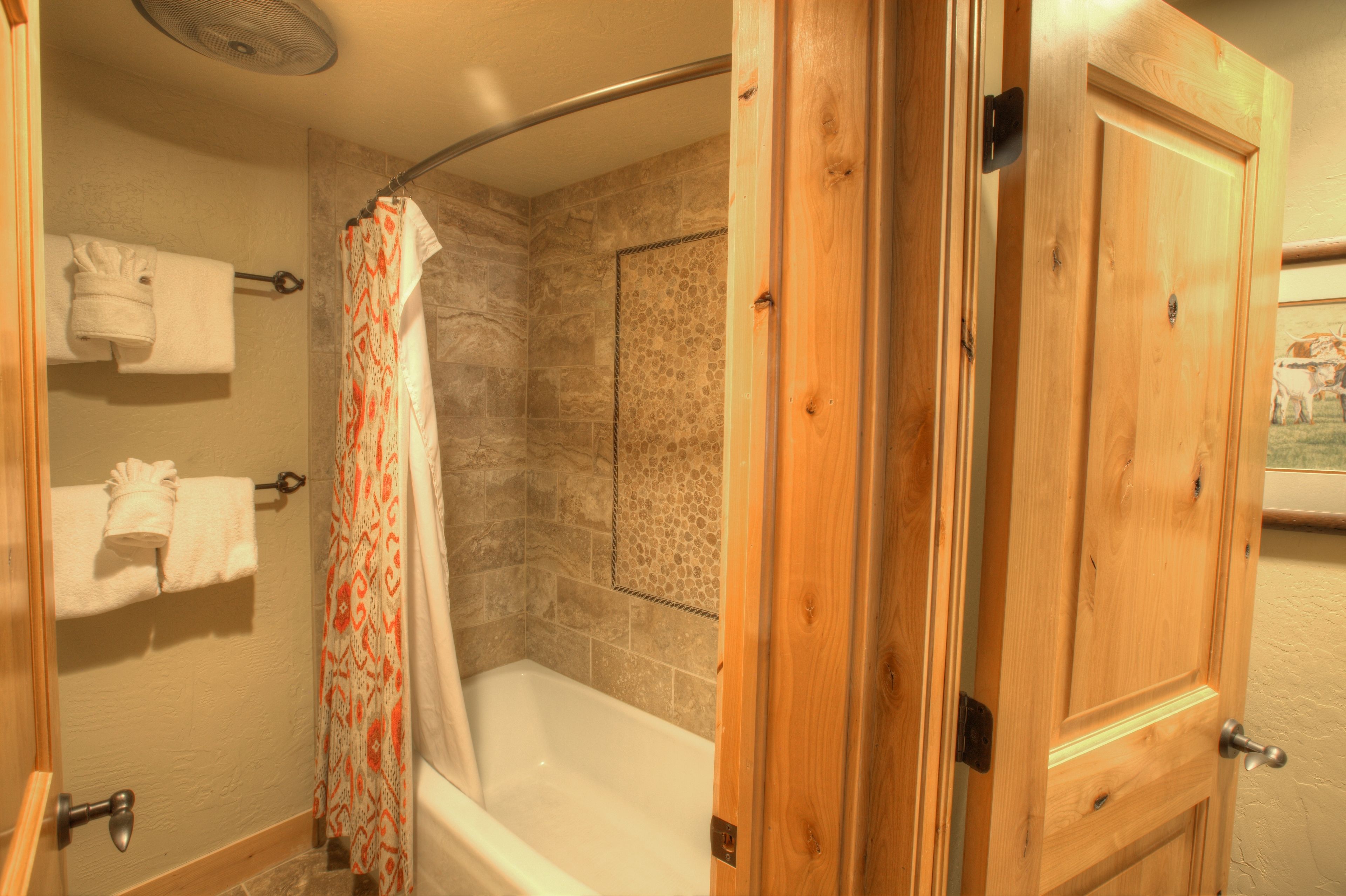 A bathroom with a shower, a bathtub, and wooden doors.