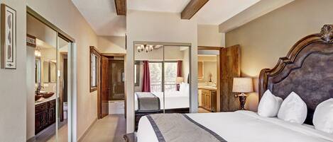 A spacious bedroom with a large bed, a wooden ceiling, and a bathroom with a glass shower.