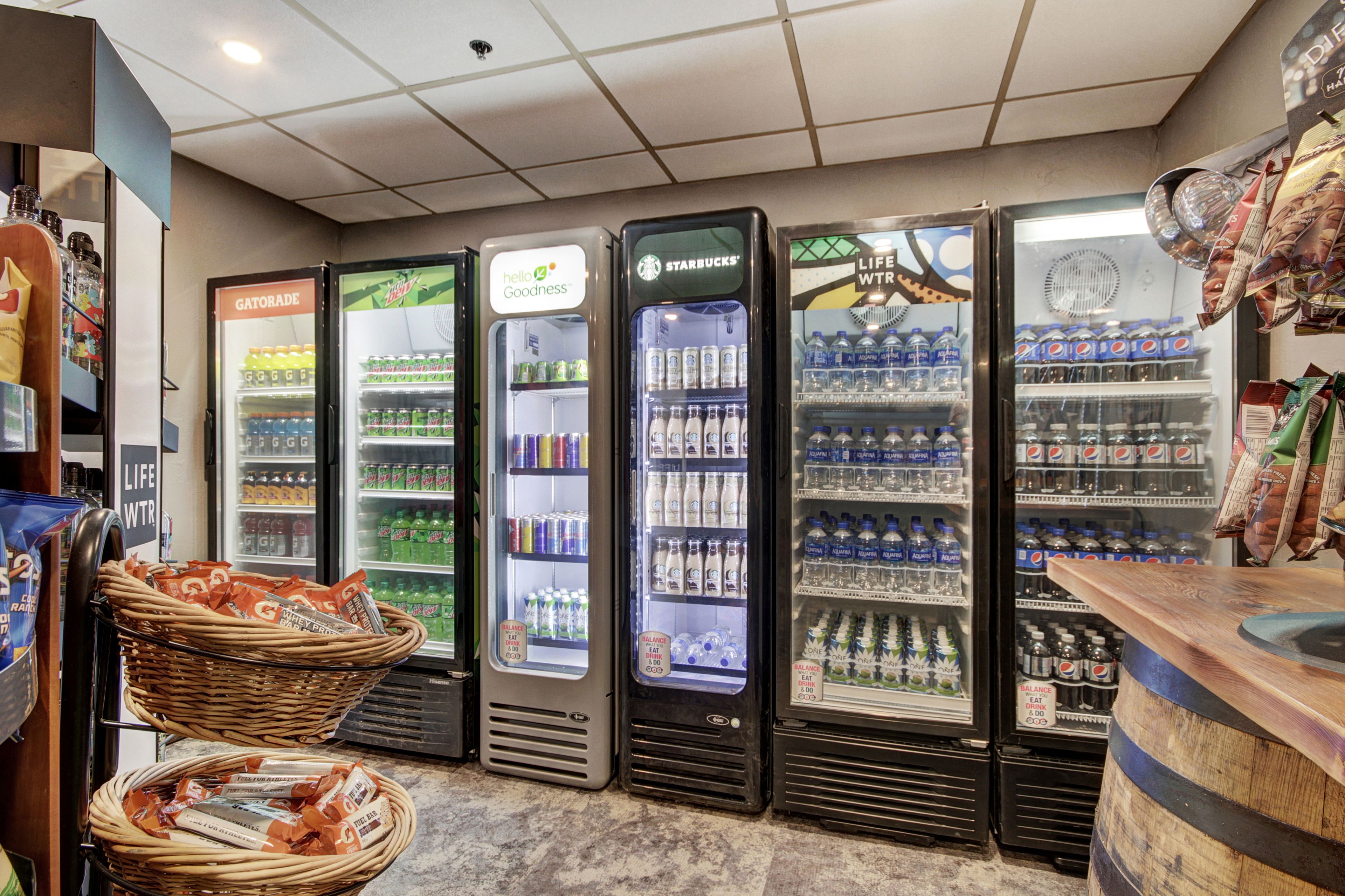 A row of beverage vending machines with various brands, including Gatorade, Life Water, and Starbucks, in a store setting.