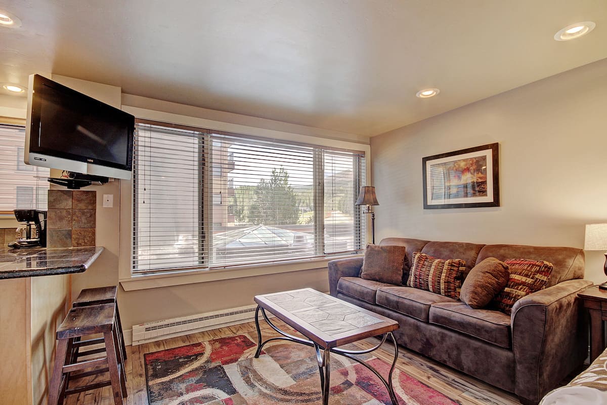 A living room with a sofa, coffee table, and a flat-screen TV mounted on the wall.