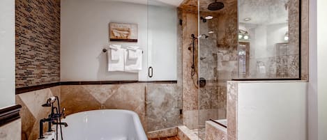 A modern bathroom with a freestanding bathtub, a glass-enclosed shower, and a tiled floor.