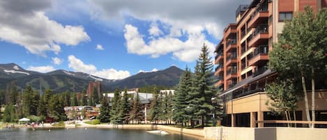 A hotel with a water feature, a mountain backdrop, and a clear sky.