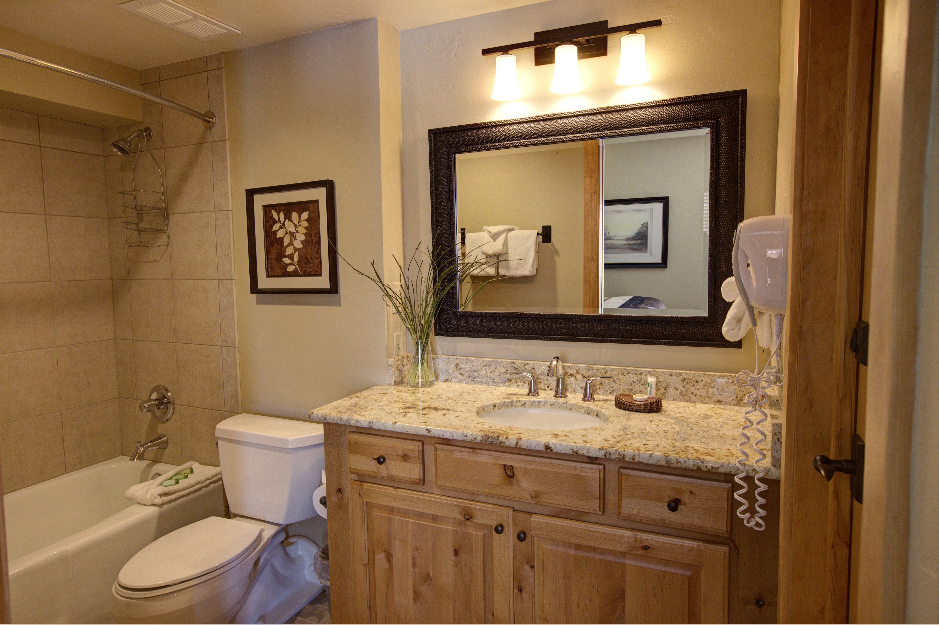 A bathroom with a bathtub, toilet, sink, and a large mirror.