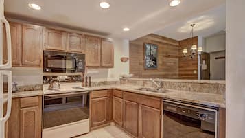 A modern kitchen with wooden cabinets, stainless steel appliances, and a granite countertop.