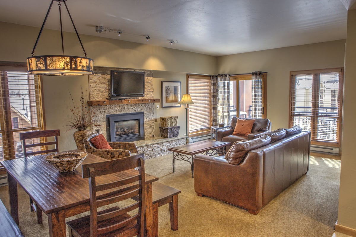 A living room with a fireplace, sofa, dining table, and chairs.