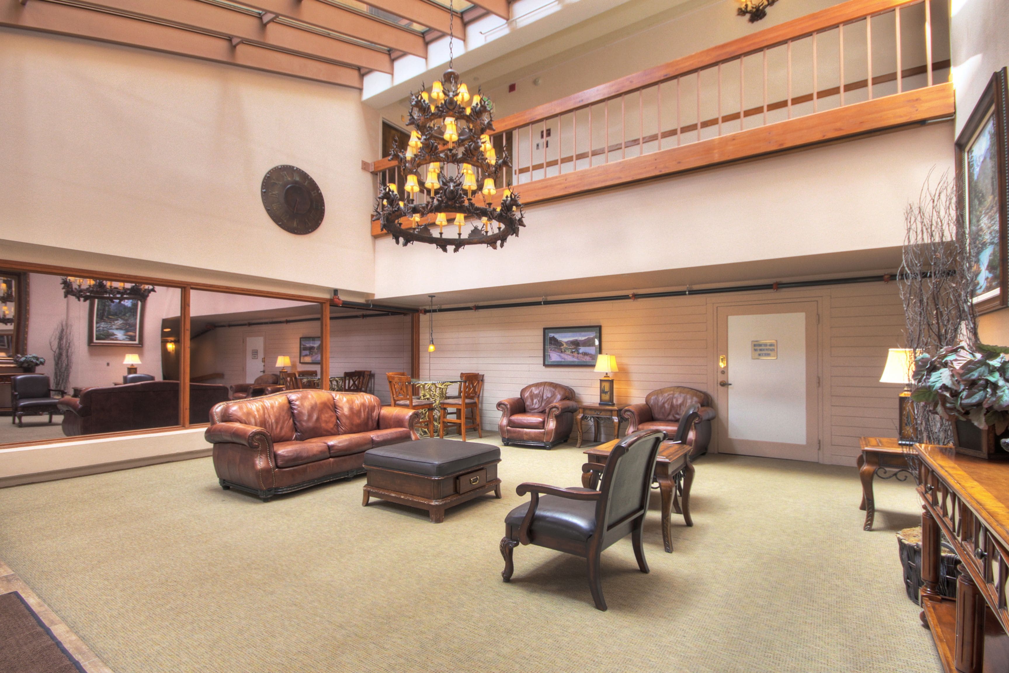 A spacious lobby with leather sofas, a wooden coffee table, and a chandelier.