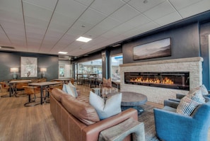 A modern lounge area with a fireplace, leather seating, and a dining area with tables and chairs.