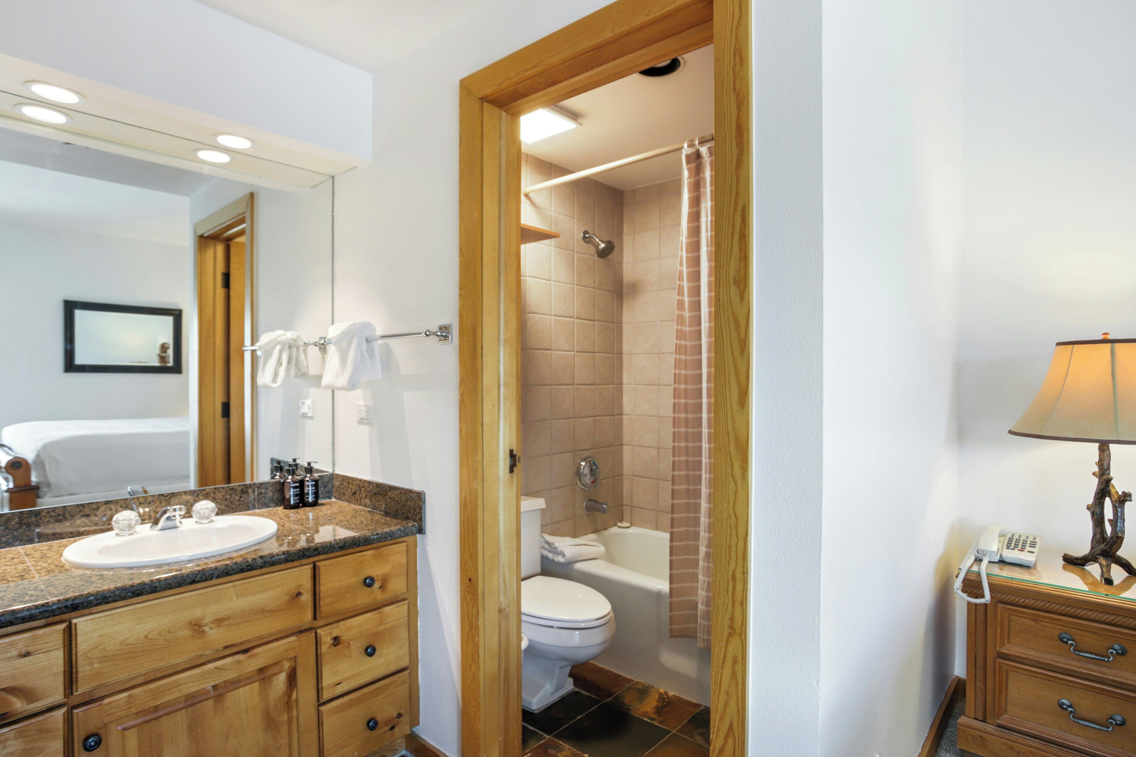A bathroom with a wooden vanity, a sink, a toilet, a bathtub, and a shower curtain.