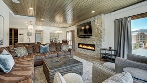 A spacious living room with a large sectional sofa, a fireplace, and a stone accent wall. - Village at Breckenridge, A Vail Resorts Property (Breckenridge)