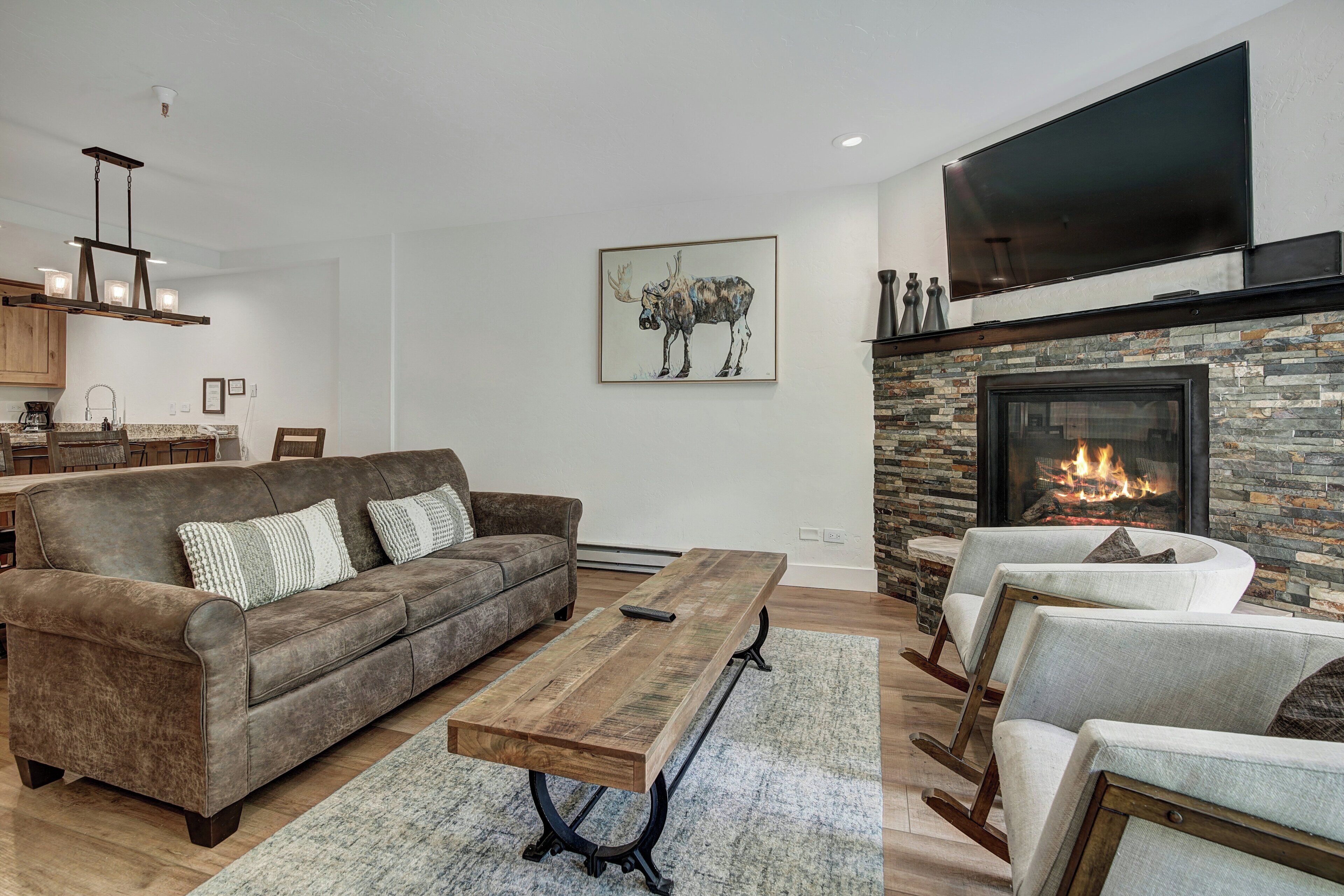 A modern living room with a fireplace, a large TV, and a cozy seating area.