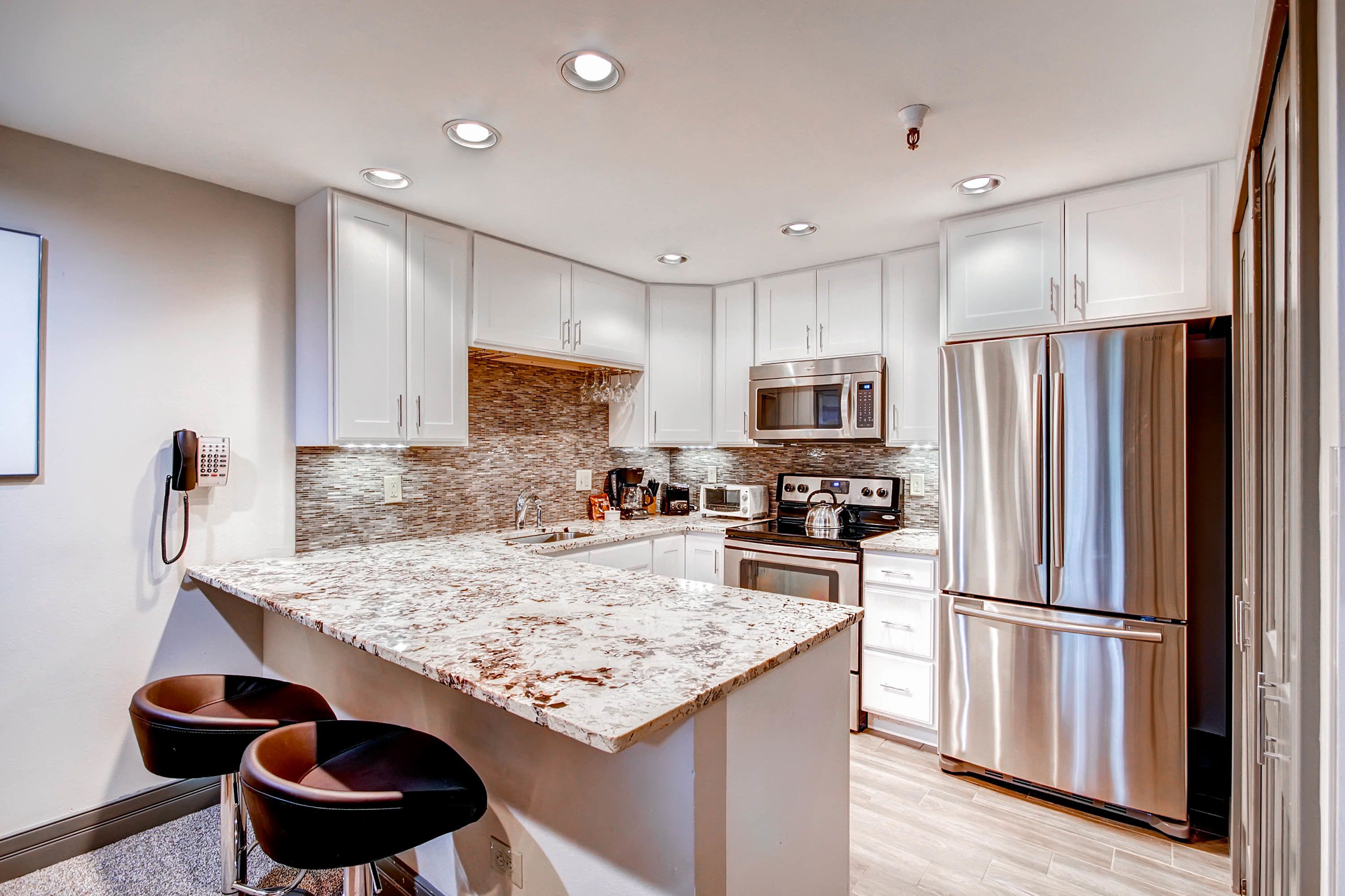A modern kitchen with white cabinets, stainless steel appliances, and a granite countertop.