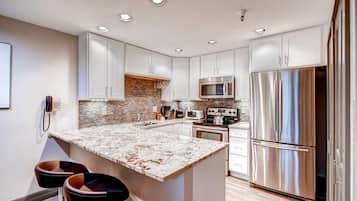 A modern kitchen with white cabinets, stainless steel appliances, and a granite countertop.