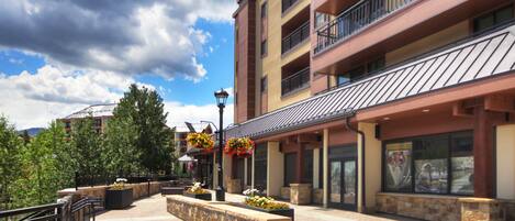 A multi-story hotel with balconies, outdoor seating areas, and a brick pathway.