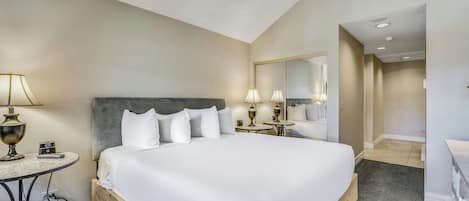 Ein Hotelzimmer mit einem großen Bett, Nachttischen, einem Spiegel und einem kleinen Tisch mit einer Lampe.