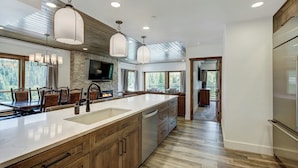 A modern kitchen with a large island, wooden cabinets, and pendant lighting. - Village at Breckenridge, A Vail Resorts Property (Breckenridge)