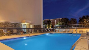 Une piscine avec des chaises longues et un mur en pierre.