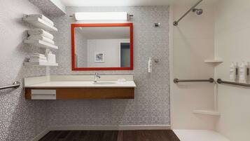 A modern bathroom with a wooden vanity, a large mirror, and a shower area.