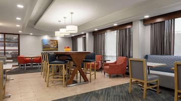 Un moderno vestíbulo de hotel con comedor, zonas de estar y grandes ventanales.