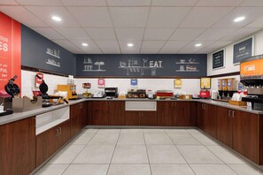 A modern kitchen with wooden cabinets, a stainless steel countertop, and various kitchen appliances.