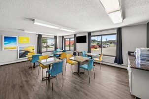Una habitación de hotel moderna con comedor, ventanas amplias y un televisor de pantalla plana.