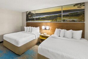 A hotel room with two beds, a large landscape painting above the headboard, a bedside table with a phone, and a blue patterned rug. - Days Inn by Wyndham Winona (Winona)