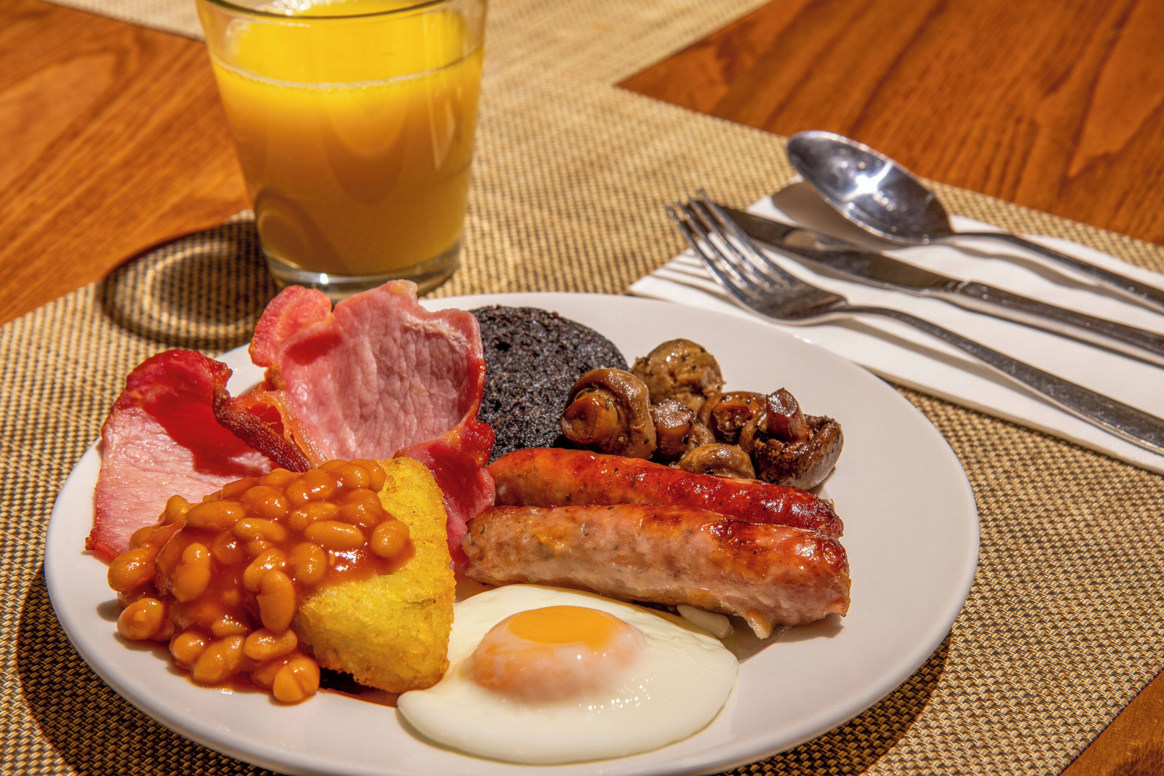 En tallerken med æg, pølser, bønner og bacon.