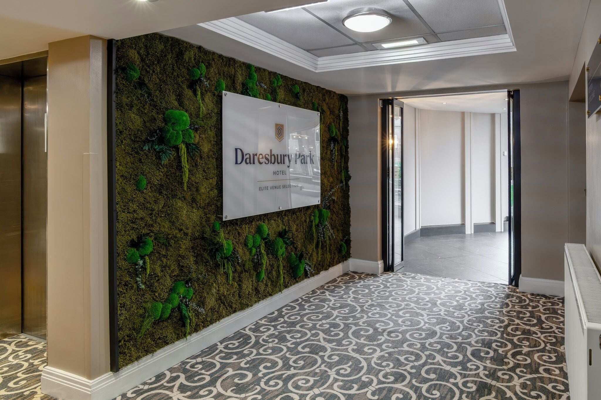 A hallway with a moss wall and a sign for Daresbury Park Hotel.