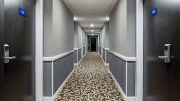 A hallway with doors numbered 161 and 160, carpeted with a patterned design, and white-framed doors.