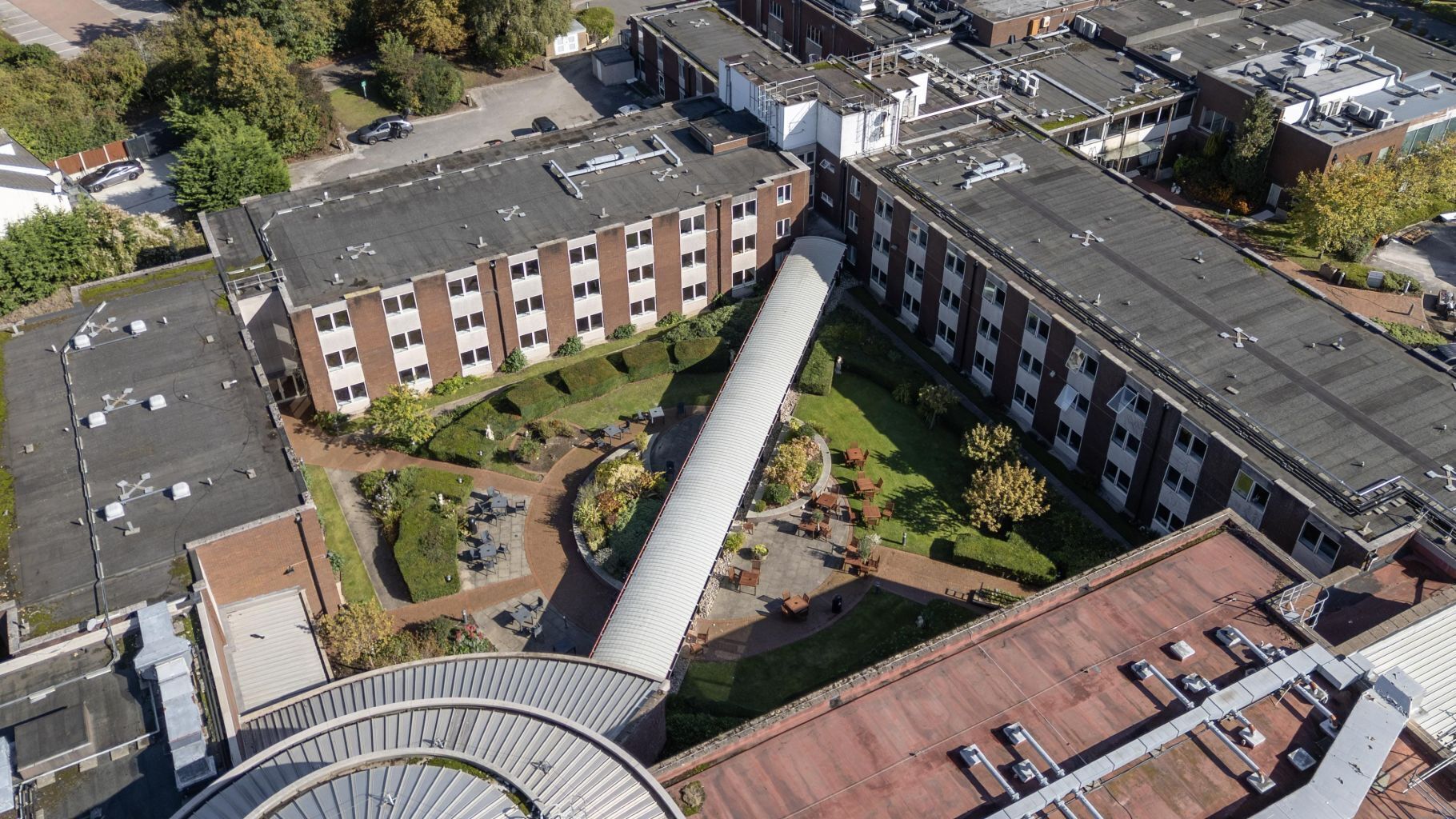 An aerial view of a building with a central courtyard, surrounded by parking areas and adjacent buildings.