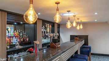 A bar area with a long counter, multiple taps, and hanging light fixtures.