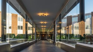 A modern corridor with glass walls, a tiled floor, and a series of ceiling lights.