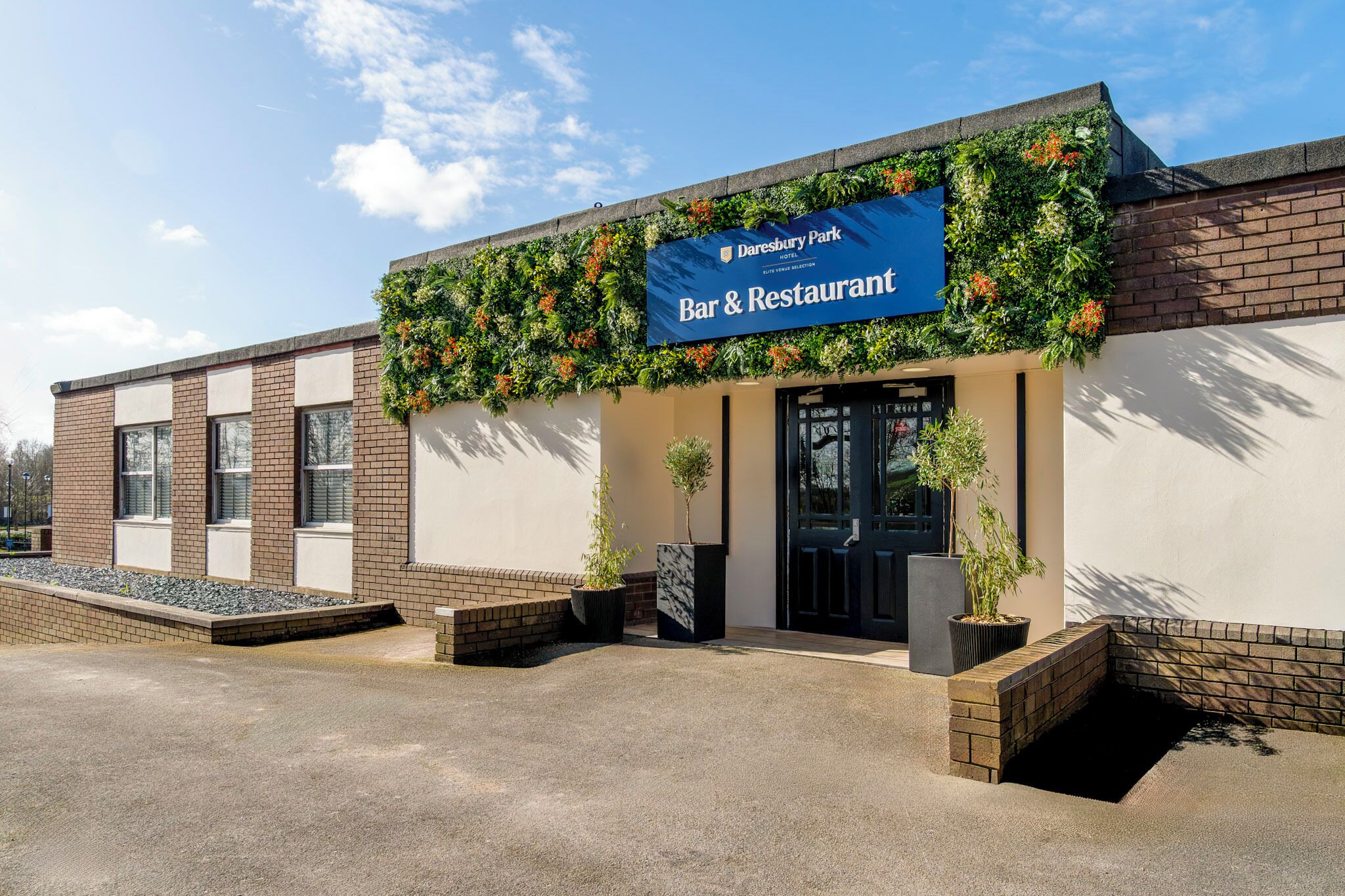 A Daresbury Park Hotel Bar & Restaurant with a brick facade, large windows, and a blue sign.