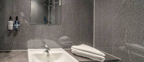 A modern bathroom with a white sink, a glass shower enclosure, and a mirror above the sink.